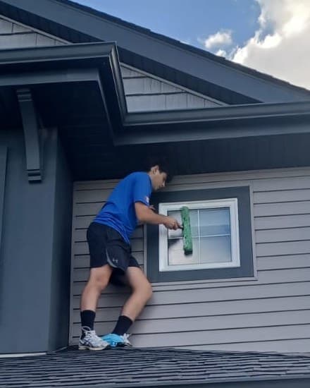 Martin from Clear Work Window Cleaning cleaning an upper-floor window from the roof